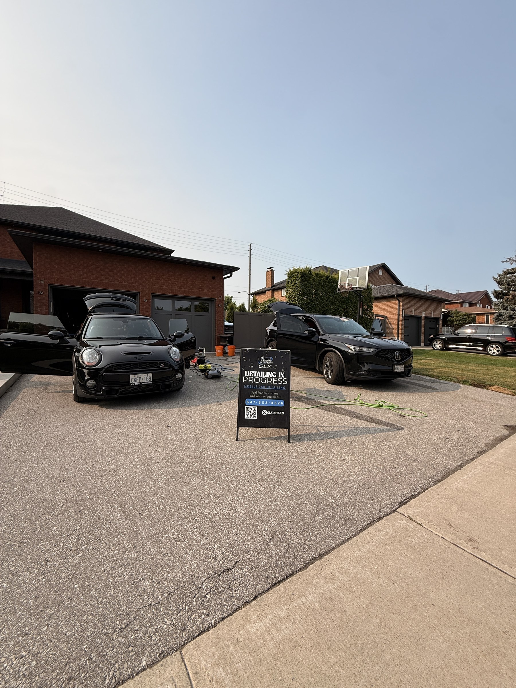 Mobile detailing setup with multiple vehicles in driveway